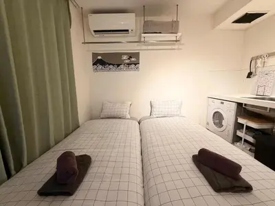 two beds in a small room with a washing machine at Shibuya Simplex 3F, sunlight and 2 beds in Tokyo