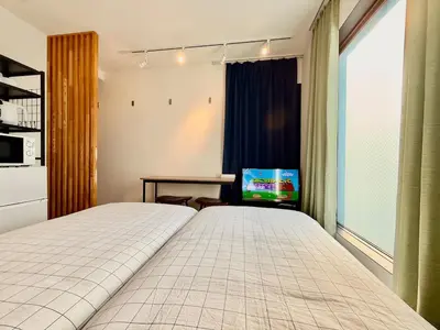 a bedroom with a bed and a table with a tv at Shibuya Simplex 3F, sunlight and 2 beds in Tokyo