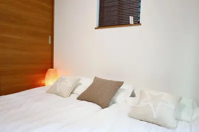 a white bed with white pillows and a wooden headboard at \u6c60\u888b4\u4e01\u76ee\u8cb8\u5207\u4e00\u8ed2\u5bb6\u6700\u5927\u4e03\u540d in Tokyo