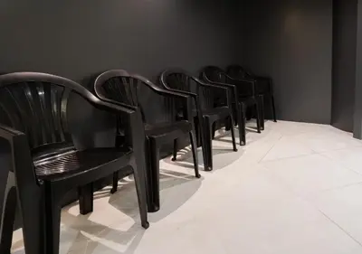 a row of black chairs lined up against a wall at Sugoi Sauna And Stay Azabu-Juban Station, Men Only in Tokyo