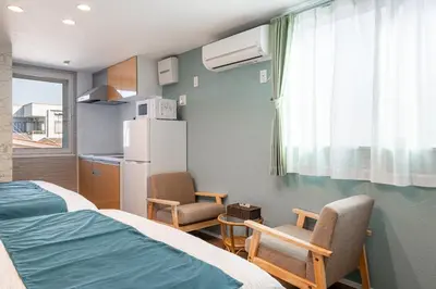 a room with a bed and two chairs and a refrigerator at Erin cort Nibankan \u30a8\u30ea\u30f3\u30b3\u30fc\u30c8\u5f10\u756a\u9928 in Tokyo
