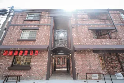 a red brick building with a door and windows at Q-ROOMS Harajuku in Tokyo