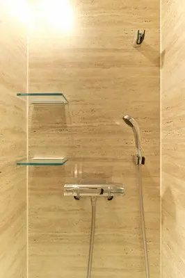 a shower with two glass shelves on a wooden wall at Q-ROOMS Harajuku in Tokyo