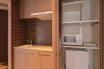 a small kitchen with a microwave and a refrigerator at Q-ROOMS Harajuku in Tokyo