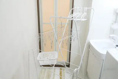 a white drying rack in a bathroom next to a sink at Grazia\u5c0f\u5ca9 201 in Tokyo