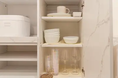 a white cupboard with dishes and bowls and glasses at \u5143\u9ebb\u5e03\u30ec\u30b8\u30c7\u30f3\u30b9106 Sakura in Tokyo
