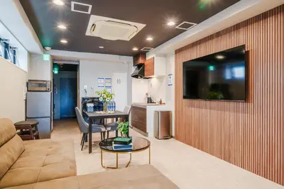 a living room with a couch and a tv on a wall at Gold HOTEL SHIBUYA in Tokyo