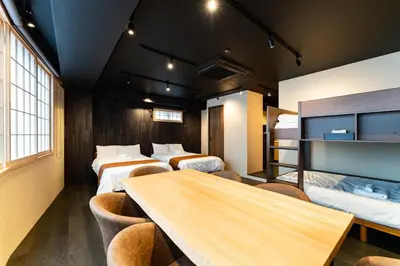 a room with four beds and a table and chairs at Koala Inn Ueno in Tokyo
