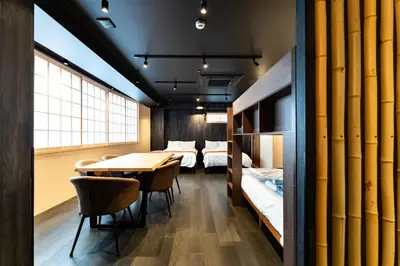a room with bunk beds and a table and chairs at Koala Inn Ueno in Tokyo