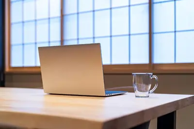 a laptop computer sitting on a table with a glass at Koala Inn Ueno in Tokyo
