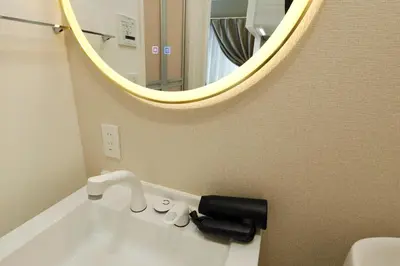 a bathroom sink with a mirror and a black hair dryer at Shimoshinmei Apartment 301 by Tranova in Tokyo