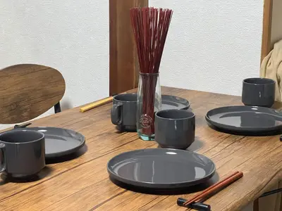 a wooden table with black plates and a vase with sticks at Tokyo Family & Pet Friendly Villa in Tokyo