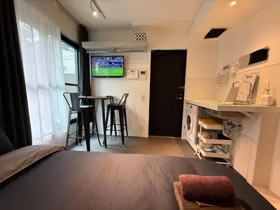 a bedroom with a bed and a table and a kitchen at Proto Shibuya Shinsen Style in Tokyo