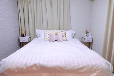 a bedroom with a white bed with two night stands at Sunlit Retreat Home-2 min from Shinjuku Station in Tokyo