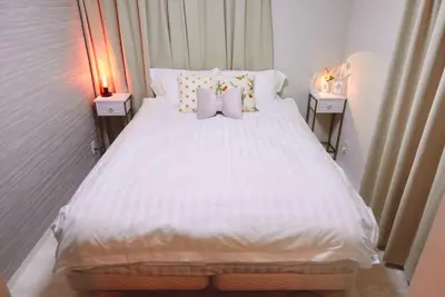a bedroom with a white bed with two night stands at Sunlit Retreat Home-2 min from Shinjuku Station in Tokyo