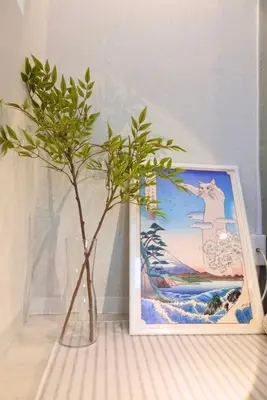 a plant in a vase next to a picture at Sunlit Retreat Home-2 min from Shinjuku Station in Tokyo
