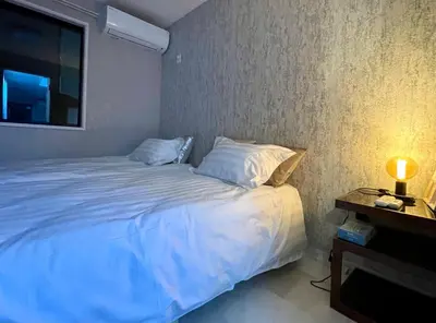 a bedroom with a white bed with a lamp and a tv at Sunlit Retreat Home-2 min from Shinjuku Station in Tokyo