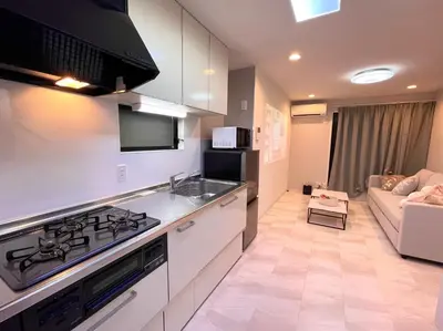 a kitchen with a stove top oven next to a couch at Sunlit Retreat Home-2 min from Shinjuku Station in Tokyo