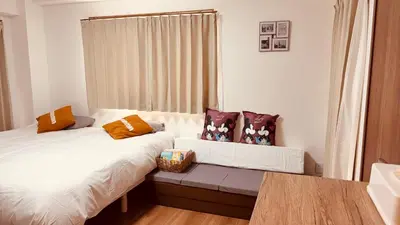 a bedroom with two beds and a bench with pillows at \u30b9\u30ab\u30a4\u30c4\u30ea\u30fc\u306e\u5bbf 502 in Tokyo