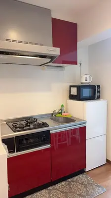 a kitchen with a red stove and a microwave at \u30b9\u30ab\u30a4\u30c4\u30ea\u30fc\u306e\u5bbf 502 in Tokyo