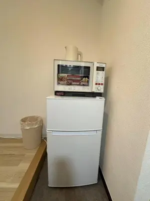 a microwave sitting on top of a white refrigerator at \u611b\u306e\u5c4b\u30db\u30c6\u30eb\u767e\u4eba\u753a in Tokyo