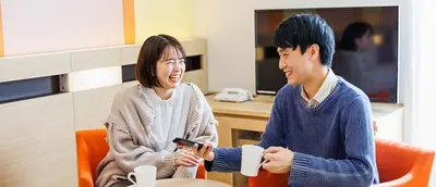 a man and a woman sitting at a table with cups at HOTEL DREAM GATE maihama - Main & Annex in Urayasu