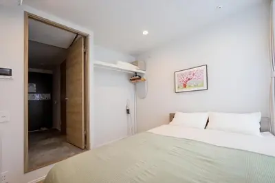 a small bedroom with a bed and a mirror at ZAITO Waseda Terra Hotel in Tokyo