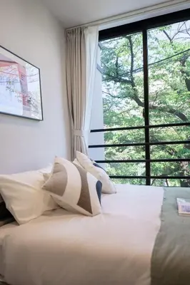 a bed in a bedroom with a large window at ZAITO Waseda Terra Hotel in Tokyo