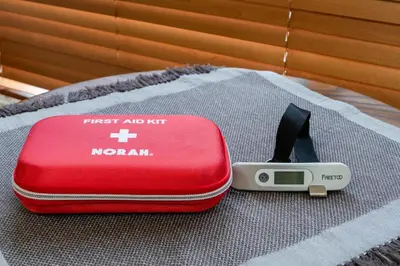 a red first aid kit and a thermometer on a blanket at THE CAMINO Nakano 202 in Tokyo