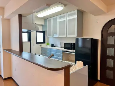 a kitchen with a black refrigerator and blue cabinets at North Tokyo Grand Inn in Tokyo