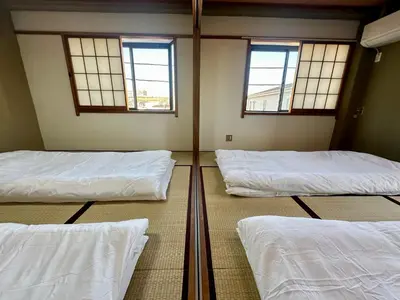 three beds in a room with three windows at North Tokyo Grand Inn in Tokyo