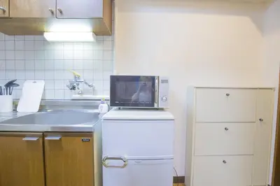 a kitchen with a microwave on top of a refrigerator at \u65b0\u5bbf\u76f4\u901a \u89b3\u5149 \u30b7\u30e7\u30c3\u30d4\u30f3\u30b0 \u30b0\u30eb\u30e1\u30b9\u30c6\u30a4 EoYg in Tokyo