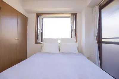 a bedroom with a bed with white pillows and a window at \u65b0\u5bbf\u76f4\u901a \u89b3\u5149 \u30b7\u30e7\u30c3\u30d4\u30f3\u30b0 \u30b0\u30eb\u30e1\u30b9\u30c6\u30a4 EoYg in Tokyo