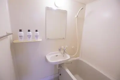 a white bathroom with a sink and a mirror at \u65b0\u5bbf\u76f4\u901a \u89b3\u5149 \u30b7\u30e7\u30c3\u30d4\u30f3\u30b0 \u30b0\u30eb\u30e1\u30b9\u30c6\u30a4 EoYg in Tokyo