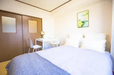 a bedroom with a white bed and a desk at \u65b0\u5bbf\u76f4\u901a \u89b3\u5149 \u30b7\u30e7\u30c3\u30d4\u30f3\u30b0 \u30b0\u30eb\u30e1\u30b9\u30c6\u30a4 EoYg in Tokyo
