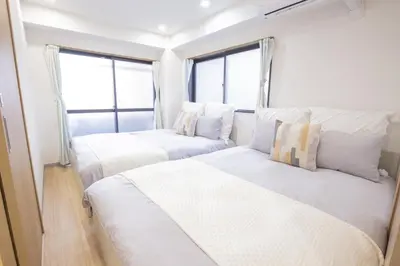 two beds in a room with two windows at \u65b0\u5bbf\u76f4\u901a \u89b3\u5149 \u30b7\u30e7\u30c3\u30d4\u30f3\u30b0 \u30b0\u30eb\u30e1\u30b9\u30c6\u30a4 EoSL in Tokyo