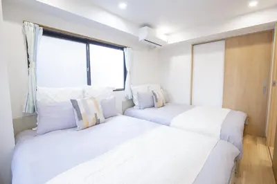 two beds in a room with two windows at \u65b0\u5bbf\u76f4\u901a \u89b3\u5149 \u30b7\u30e7\u30c3\u30d4\u30f3\u30b0 \u30b0\u30eb\u30e1\u30b9\u30c6\u30a4 EoSL in Tokyo
