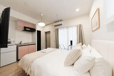 a bedroom with a white bed and a kitchen at shinjuku house in Tokyo