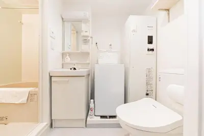 a white bathroom with a toilet and a sink at shinjuku house in Tokyo