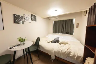 a bedroom with a bed and a table and a window at \u30d9\u30eb\u30a8\u30a2\u5927\u4e45\u4fdd205 in Tokyo
