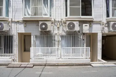 a white brick building with air conditioners on it at shinjuku-ookubo Apartment room101 in Tokyo
