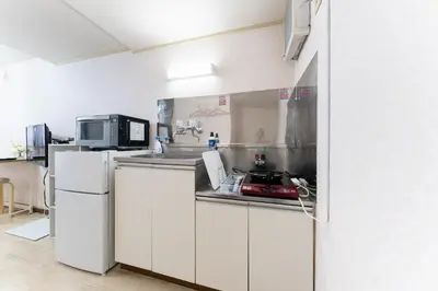 a kitchen with white cabinets and a microwave at shinjuku-ookubo Apartment room101 in Tokyo