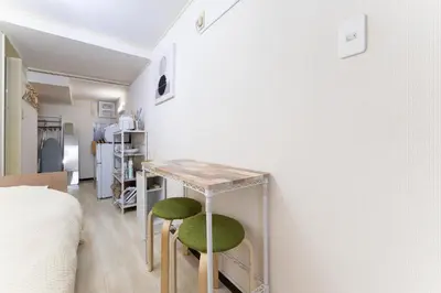 a room with a table and two green stools at shinjuku-ookubo Apartment room102 in Tokyo
