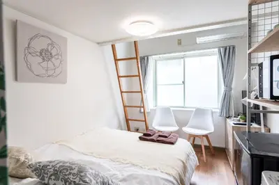 a bedroom with a bed and two white chairs at shinjuku-ookubo Apartment room202 in Tokyo