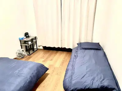 a bedroom with two beds and a curtain at Tokyo West Shinjuku close to Shinjuku Chuo Park in Tokyo