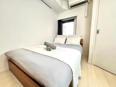 a bedroom with a bed with white sheets and a window at Shinjuku City Apt, 2DB , Free WiFi in Tokyo