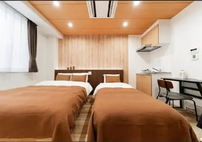 two beds in a room with a kitchen at Oshiage SAIEI Hotel 402 in Tokyo