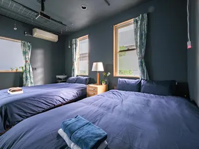 two beds in a bedroom with blue walls and windows at Tokyo Tower Hostel Shiba Park - \u6771\u4eac\u30bf\u30ef\u30fc\u30db\u30b9\u30c6\u30eb\u829d\u516c\u5712 - \u7fbd\u7530\u7a7a\u6e2f\u307e\u3067\u30a2\u30af\u30bb\u30b9\u629c\u7fa4 \u6771\u4eac\u30bf\u30ef\u30fc\u5f92\u6b6915\u5206 \u7121\u6599Wi-Fi in Tokyo