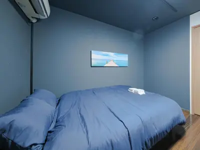 a bed in a room with a blue wall at Tokyo Tower Hostel Shiba Park - \u6771\u4eac\u30bf\u30ef\u30fc\u30db\u30b9\u30c6\u30eb\u829d\u516c\u5712 - \u7fbd\u7530\u7a7a\u6e2f\u307e\u3067\u30a2\u30af\u30bb\u30b9\u629c\u7fa4 \u6771\u4eac\u30bf\u30ef\u30fc\u5f92\u6b6915\u5206 \u7121\u6599Wi-Fi in Tokyo