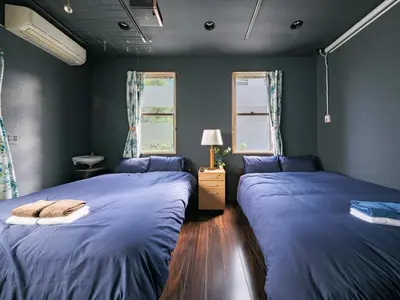 two beds in a room with blue walls and windows at Tokyo Tower Hostel Shiba Park - \u6771\u4eac\u30bf\u30ef\u30fc\u30db\u30b9\u30c6\u30eb\u829d\u516c\u5712 - \u7fbd\u7530\u7a7a\u6e2f\u307e\u3067\u30a2\u30af\u30bb\u30b9\u629c\u7fa4 \u6771\u4eac\u30bf\u30ef\u30fc\u5f92\u6b6915\u5206 \u7121\u6599Wi-Fi in Tokyo